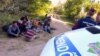 Afghan and Pakistani migrants sit in front of Hungarian police officers at the Hungarian-Serbian border in June.