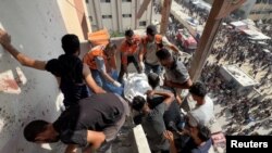 Спасители и цивилни работят за изваждането на тялото на оператора Хусам ал-Масри, който е работил за Ройтерс. Масри и още трима журналисти бяха убити при израелски удар върху болницата „Насър“ в Хан Юнис, в южната част на Ивицата Газа. 25 август 2025 г.