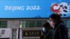 China -- People walk past a banner with a sign of Beijing 2022 Winter Olympic Games, 100 days ahead of the opening of the event, in Beijing, China October 27, 2021. REUTERS/Tingshu Wang