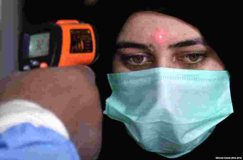 Проверка на температурата на еден патник откако владата ги олесни рестриктивните мерки на коронавирус, во Карачи, Пакистан, на 20 мај 2020 година. Неколку држави низ целиот свет започнаа да ги олеснуваат ограничувањата на пандемијата за заклучување на пандемијата ковид-19 во обид да ги рестартираат своите економии и да им помогнат на луѓето во нивните секојдневни рутини по избувнувањето на пандемијата на коронавирус.