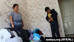 Сын Гульбахиры Пернехан примеряет старую школьную форму, которая оказалась ему мала. Шымкент, 13 августа 2016 года.