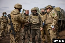 Ukrainian President Volodymyr Zelenskiy (center) greets soldiers during his working visit to the eastern conflict zone on April 8.