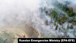 Tűzoltók próbálják megfékezni a lángokat Jakutföldön 2021. július 21-én