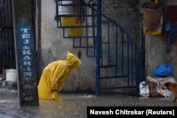 Женщина в плаще пробирается по затопленной улице в Катманду, Непал, 4 октября 2025 года