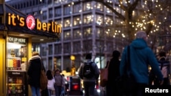 Njerëzit duke ecur pranë një tezge të qebapit në Kurfuerstendam, Berlin. 