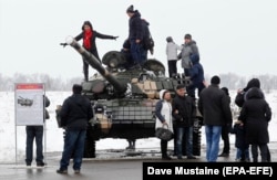 Local people pose on a T-72 tank of the separatist forces during celebrations of Defender of the Fatherland Day at the former airport in Luhansk in February 2020.