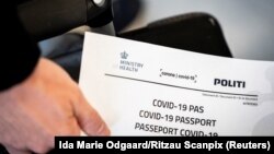 Një person në Daminarkë duke mbajtur në duar në pasaportë për koronavirusin të lëshuar nga autoritetet daneze. Fotografi nga arkivi.
