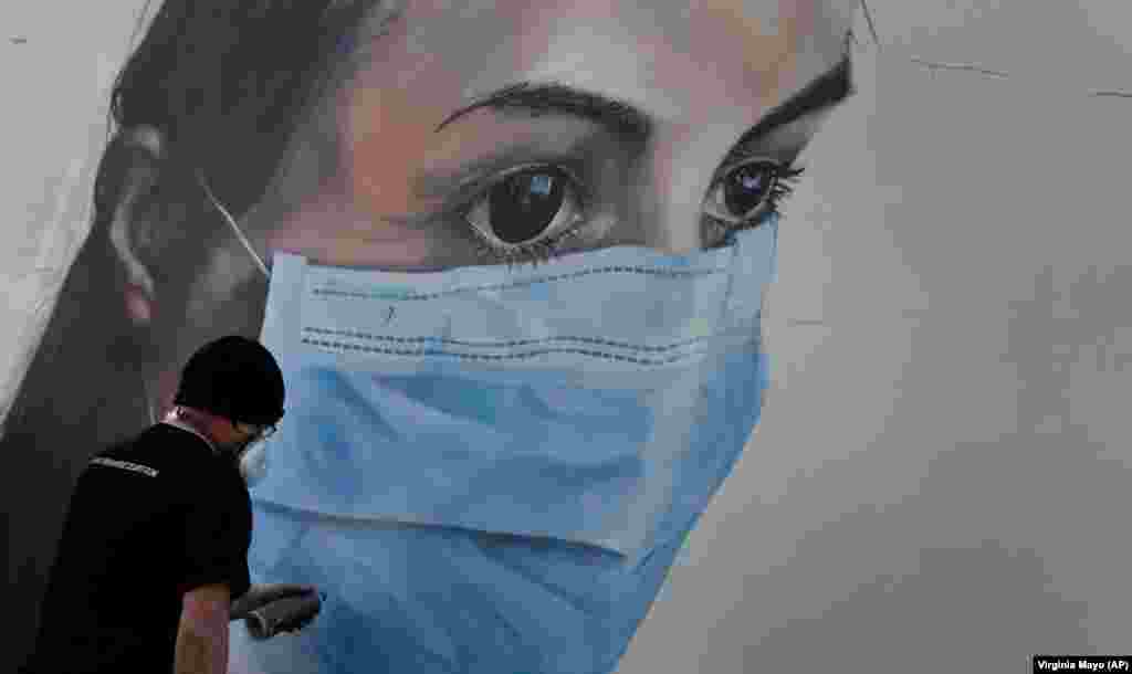 Уметникот на графити Брам Де Керт работи на уличен мурал на медицинска сестра во Антверпен, Белгија.