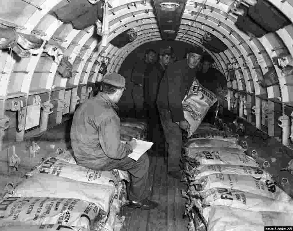 Американски войниик проверява документите и контролира натоварването с брашно на самолет &quot;C-47 Скайтрейн&quot; на главното летище във Франкфурт на Майн на 29 юни, 1948 г. Това е главният снабдителен център за Берлинския въздушен мост.&nbsp;