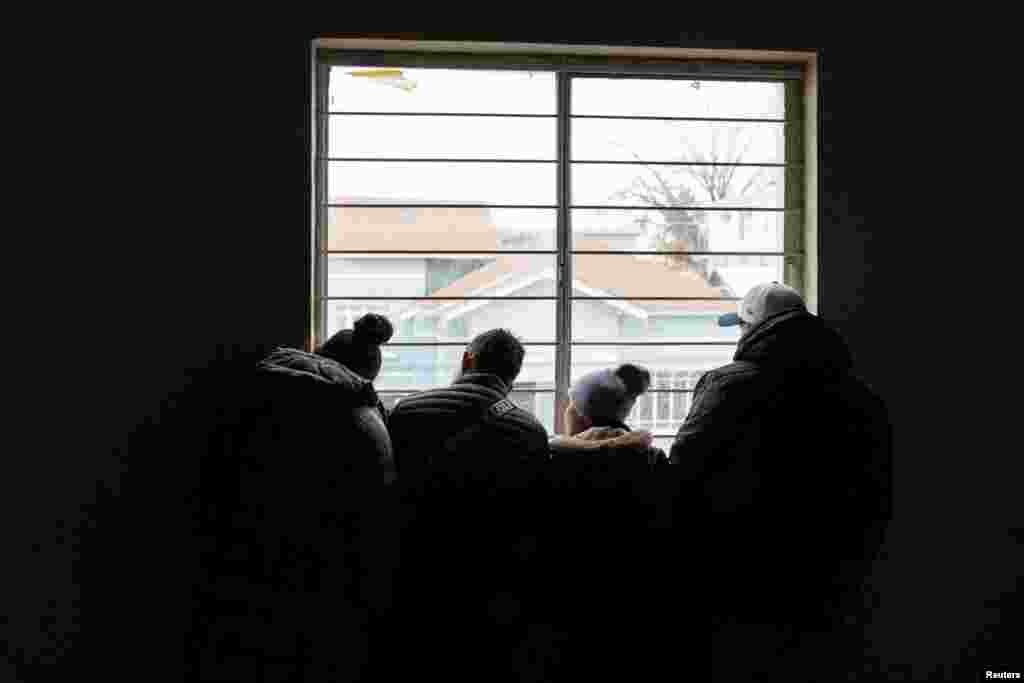 Azilkërkuesit shikojnë nga dritarja e një strehimoreje emigrantësh pasi morën email nga Dogana dhe Mbrojtja Kufitare e SHBA-së (CBP), që i informonte&nbsp;ata se takimet e tyre ishin anuluar, në ditën e inaugurimit për mandatin e dytë presidencial të Trumpit. Meksikë, 20 janar.