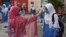 A teacher checks the body temperature of students at a government school in Lahore on September 15. 