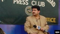 FILE: Hamid Mir recoded his television show outside the Islamabad Press Club to protest a ban by military dictator Pervez Musharraf in 2007.