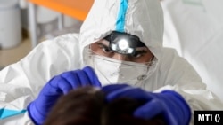  A Debreceni Egyetem szakembere egy nő orrnyálkahártyájának mintáját veszi koronavírus vizsgálatra az intézmény egyik mintavételi pontján 2020. május 13-án.
