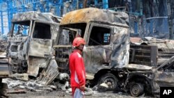 Un angajat al serviciilor de urgență în fața vehiculelor arse în urma exploziei masive ș ia incendiului care au afectat portul Shahid Rajai din apropierea orașului port Bandar Abbas din sudul Iranului, pe 26 aprilie.