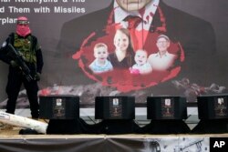 Un militant se află lângă sicriele care conțin trupurile ostaticilor, de la dreapta la stânga, Shiri Bibas, cei doi copii ai ei, Ariel și Kfir, și Oded Lifshitz, care avea 83 de ani când a fost răpit, înainte ca aceștia să fie predați Crucii Roșii în Khan Younis.