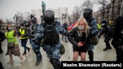 Служители на силите за сигурност задържат протестираща по време на демонстрациите в Русия