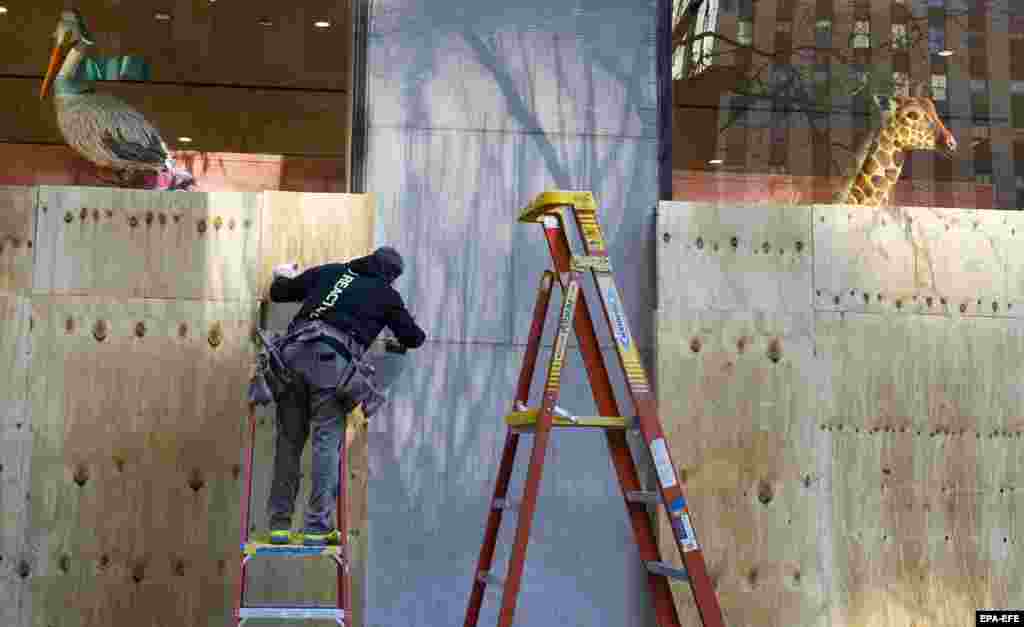 Работник става иверица над излогот на продавницата во Њујорк на 2 ноември 2020 година. 