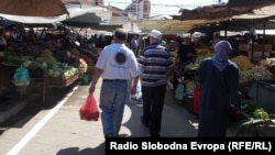 Илустрација: Луѓе се движат покрај тезги на пазар. 