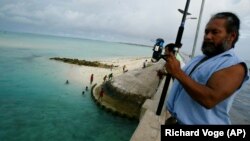 Kiribatin, a Tarawa-atoll hídján horgászik egy férfi 2004. március 30-án.