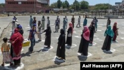 People stand in designated areas marked on the ground to maintain social distance as they receive free food from volunteers of Chhipa Welfare Association during a government-imposed nationwide lockdown in Karachi on March 27.