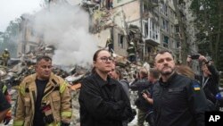 Украинската премиерка Јулија Свириденко, во центар, и министерот за внатрешни работи Игор Клименко, десно, го посетуваат местото на повеќекатна станбена зграда уништена од руски ракетен напад во Киев, Украина, четврток, 31 јули 2025 година.
