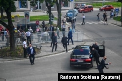 Служители на охраната преместват Фицо в кола след стрелбата