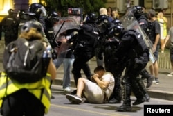 Сербские полицейские задерживают демонстранта во время столкновений между сторонниками правящей партии и антиправительственными протестующими в Белграде, Сербия, 13 августа 2025 года