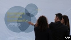Emberek az Európai Politikai Közösség csúcstalálkozójának logója előtt Granadában, Dél-Spanyolországban, a Palacio de Congresosban 2023. október 4-én