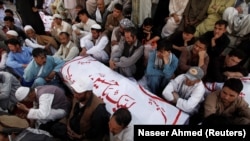 FILE: Shi'ite Muslim men from Pakistan's ethnic Hazara minority mourn around the coffins of their relatives, who were killed in a shooting attack, in Quetta in October 2017.