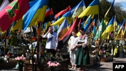 O familie, rugându-se de Paște la mormântul unui soldat ucrainean din cimitirul militar din Lvov, 20 aprilie 2025 