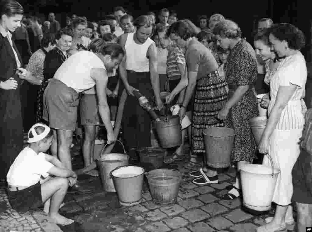 Жители на Западен Берлин чакат, за да напълнят кофите си с вода на 3 юли, 1948 г. След като съветските части блокират доставките, опашките стават нещо обичайно.&nbsp;