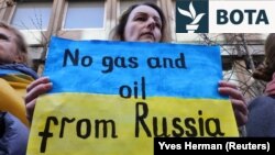 Një grua mban një pankartë gjatë një demonstrate në mbështetje të Ukrainës pranë Ambasadës Gjermane në Bruksel. (Fotografi nga arkivi)