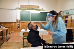 A Semmelweis Egyetem koronavírus-tesztet végző szülésznő hallgatója mintát vesz egy pedagógustól.
