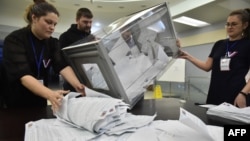 Membrii unei comisii electorale locale numărând buletinele de vot la o secție din Novosibirsk, Rusia, pe 17 martie.