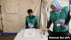 FILE: Afghan employees of the Independent Election Commission (IEC) wait to register residents at a voter registration center for the upcoming parliamentary and district council elections in Kabul.