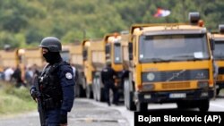 Një pjesëtar i policisë speciale të Kosovës qëndron pranë kamionëve në një rrugë pranë pikës kufitare veriore të Kosovës në Jarinje, 20 shtator 2021. 