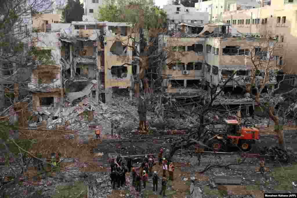 Israeli rescue workers stand amid buildings damaged in a residential area following an Iranian strike on Tel Aviv on June 16.