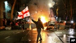 În fața unei baricade în flăcări lângă clădirea parlamentului georgian din Tbilisi, la 9 martie.
