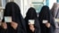 Burqa-clad women show ID cards as they wait to cast their votes in Kandahar. Is their willingness to participate a sign of Taliban weakness?