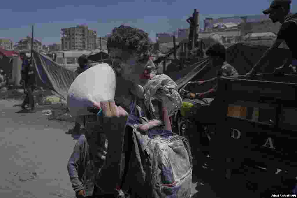 Un băiat cară un sac de făină obținut de la un convoi umanitar care a ajuns la Gaza City prin nordul Fășiei Gaza, marți, pe 22 iulie. 