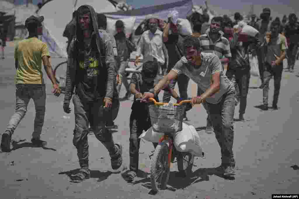 Tineri care cară cu bicicleta un sac de făină. Lipsa aprovizionărilor esențiale a dus la o explozie a prețurilor în Gaza. Potrivit BBC, un rezident în Gaza a declarat „avem nevoie de 300 de șekeli israelieni (aproximativ 75 de euro) doar pentru făină!”