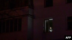 Un bărbat ține o lanternă la fereastra apartamentului său, în timpul deconectării programate a curentului electric la Varnita, în Zona de Securitate, 17 ianuarie 2025.