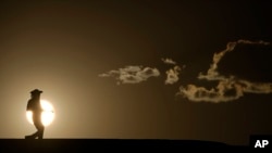 Egy ember sétál egy ösvényen napnyugtakor a Death Valley Nemzeti Parkban, Kaliforniában 2023. július 16-án. A Climate Central jelentése szerint a Földön minden öt emberből négy bármely korábbinál melegebb júliussal találkozott tavaly