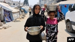 Деца носят съдове със супа от леща, която са получили като хуманитарна помощ, в Газа, 25 юли 2025 г. 