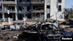 Pogled na izgorjele automobile i oštećenu zgradu na mjestu udara nakon iranskog raketnog napada na Izrael, u Be'er Shevi, Izrael, 20. juna 2025.