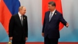 Лидер Китая Си Цзиньпин приглашает президента России Владимира Путина присоединиться к нему после фотосессии на саммите Шанхайской организации сотрудничества (ШОС) в Тяньцзине. 1 сентября 2025 года