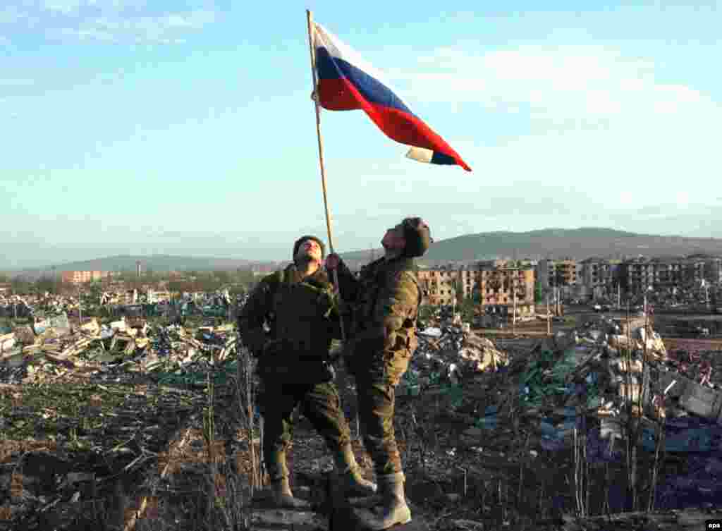 Troops raise a Russian flag in the center of Grozny in February 2000. By the time federal forces recaptured the city, much of it had been reduced to ruins by Russian bombs and by other weapons in the fighting.