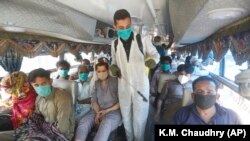 A volunteer sprays disinfectant on passengers traveling to their villages to celebrate the upcoming Eid al-Fitr holiday that marks the end of the Muslim holy fasting month of Ramadan on May 22.
