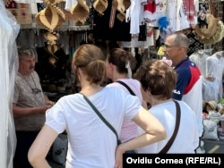 Molnoș Ferenc (plan îndepărtat) vorbește cu unii dintre puținii turiști care mai opresc zilele acestea pentru cumpărarea unui suvenir.