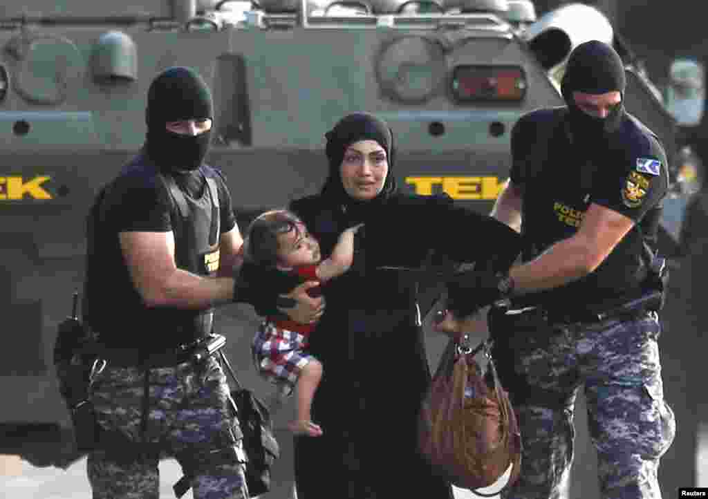 Венгерские полицейские ведут женщину-беженку с ребенком подальше от мест столкновений. 16 сентября